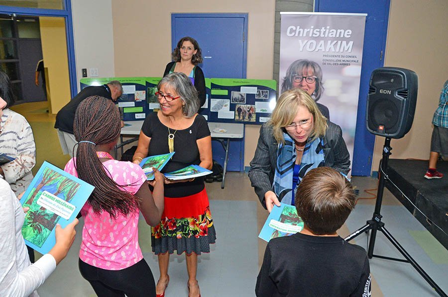 Laval city councillor hand out copies of L’Arbre millénaire to grade five students from École Boisjoili.