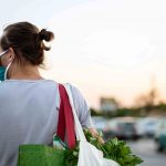 Man wearing protective medical mask and carrying white reusable