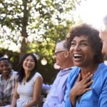 Group Of Mature Friends Socializing In Backyard Together