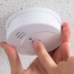 Person’s Hand Installing Smoke Detector On Ceiling
