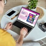 Mockup white screen laptop woman using computer while sitting at table at home, back view